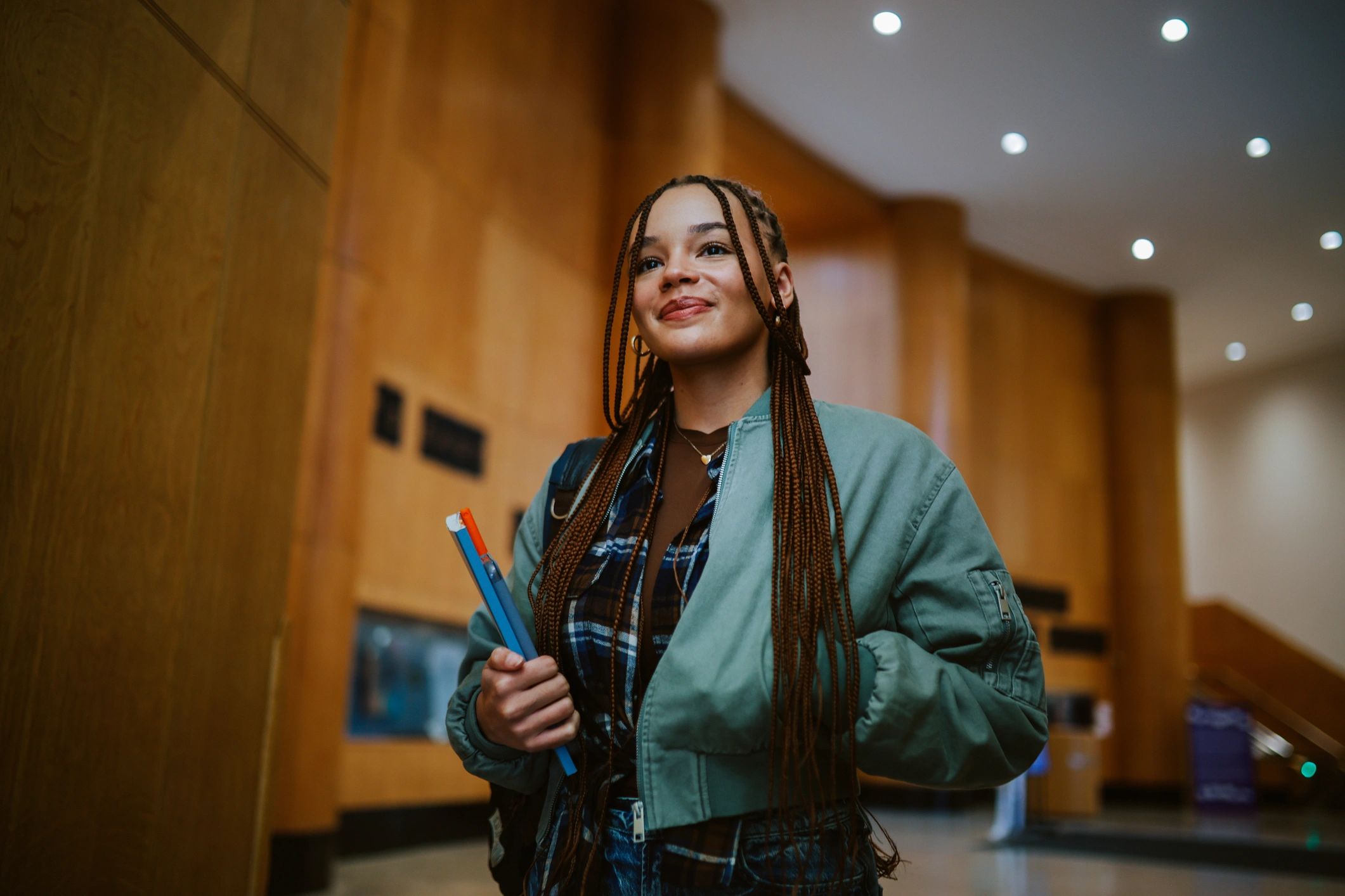 Student walking into a library with a laptop